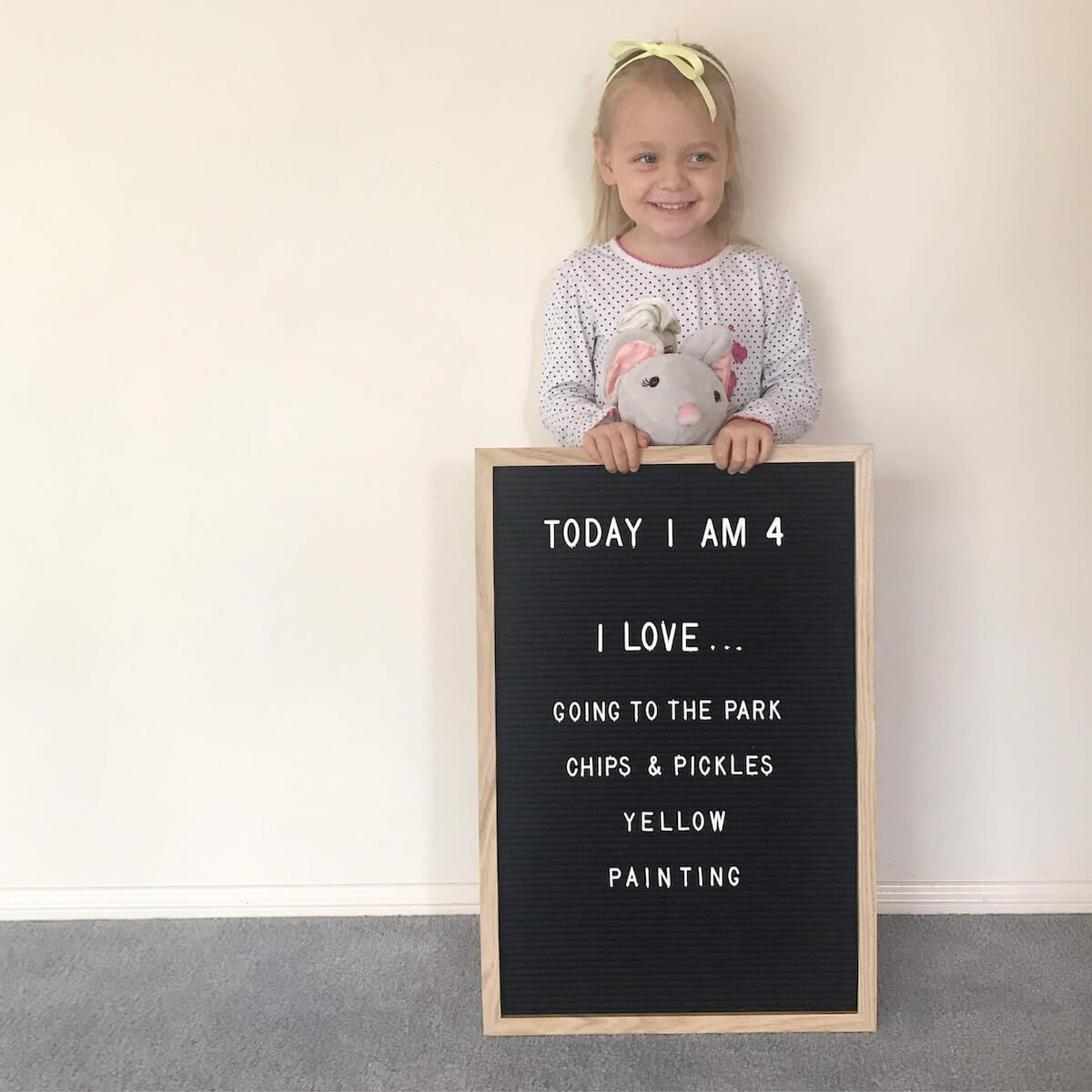 Child holding a large letterboard to celebrate her 4th birthday with her favourite things listed.
