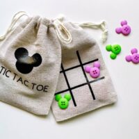 two tic tac toe bags with green and purple mickey mouse buttons.