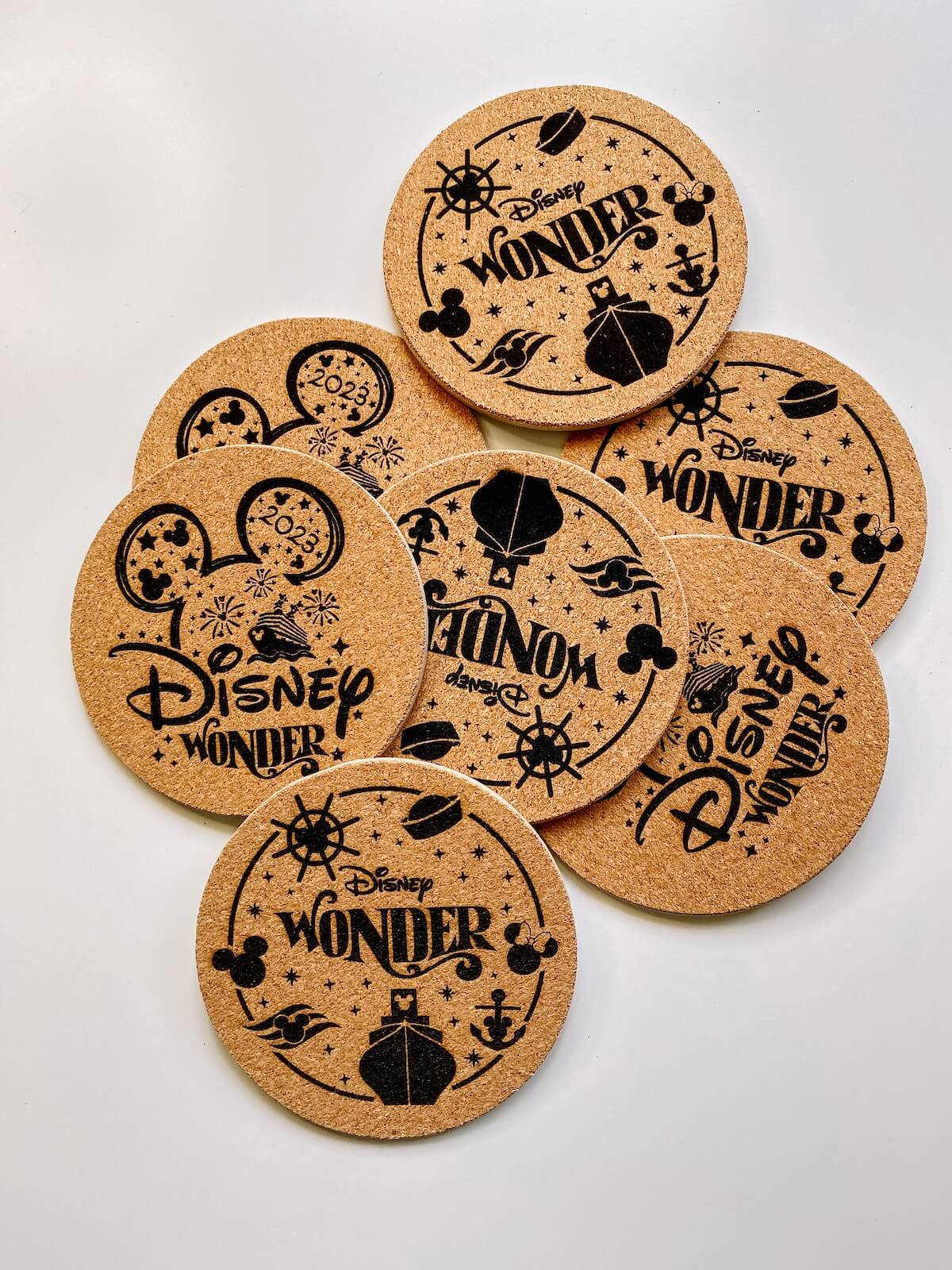 Pile of laser engraved cork coasters with disney cruise designs.