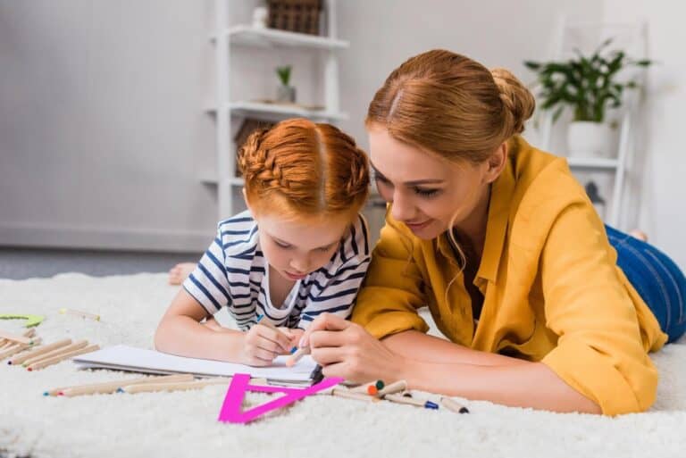 mother and child colouring together on the floor.