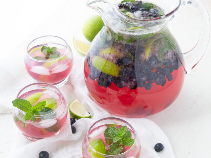 pitcher of blueberry mojito and glasses.
