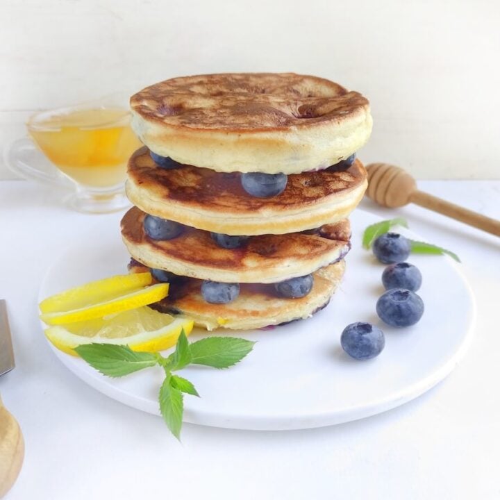 stack of blueberry lemon pancakes on white plate.
