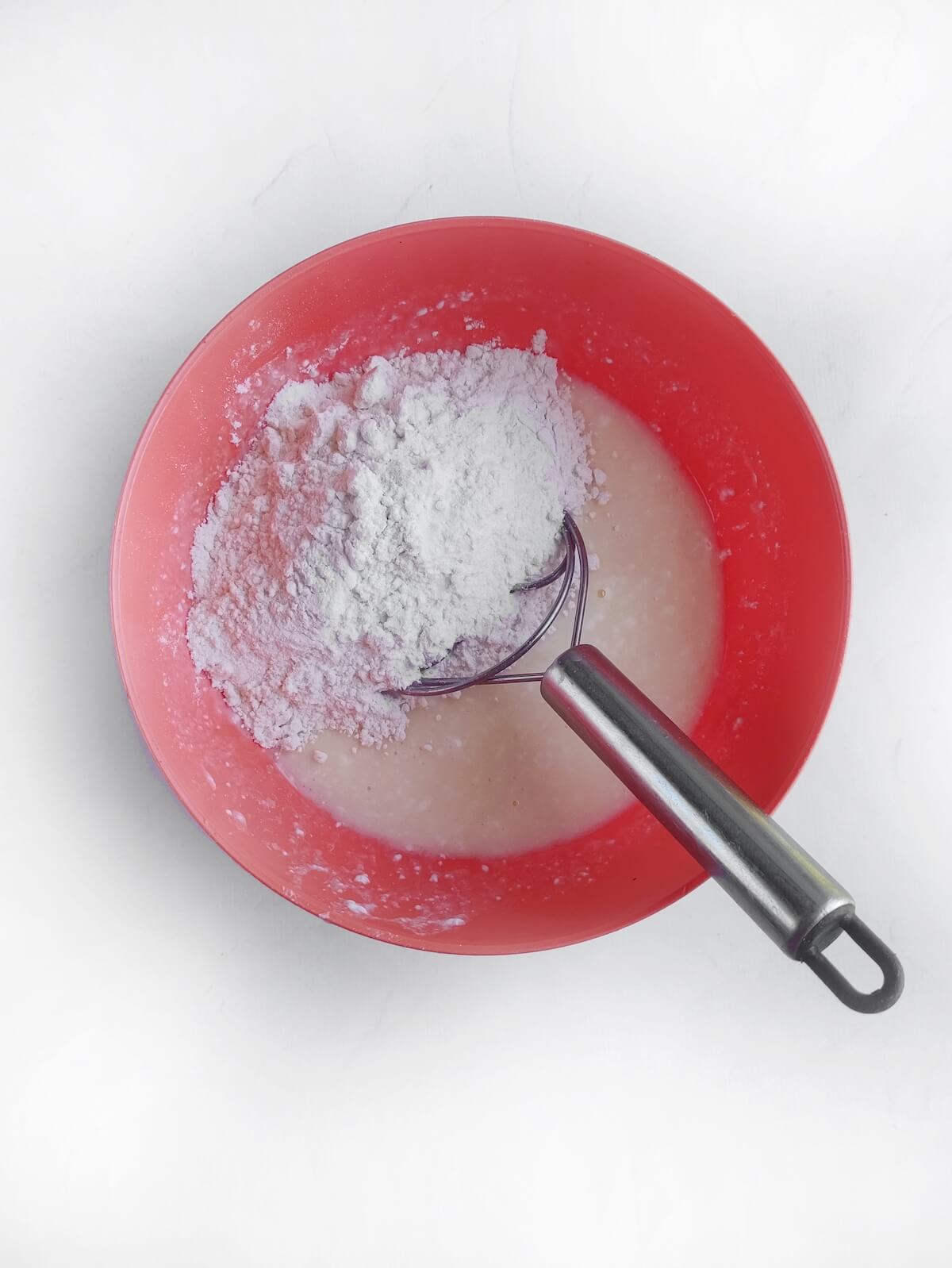 mixing pancake batter in red bowl.