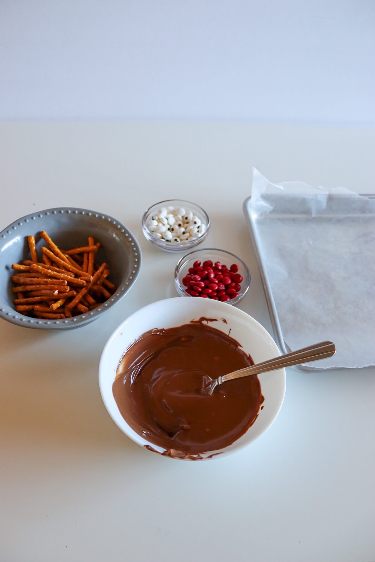 No-Bake Pretzel Reindeers 3 ingredients for pretzel reindeers with melted chocolate.