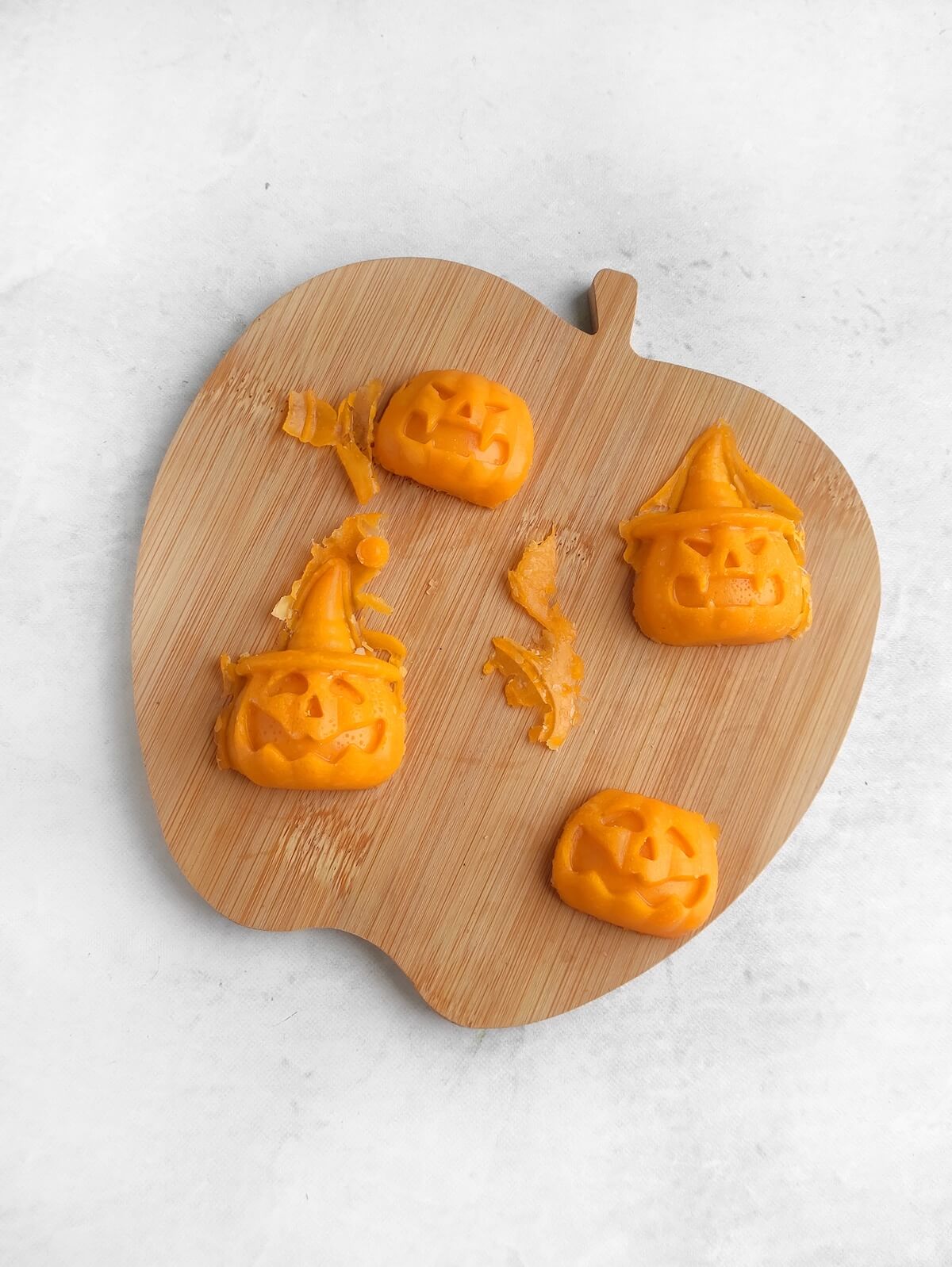 Jack-o’-Lantern Halloween Cheese Shapes 5 halloween cheese shapes on chopping board.