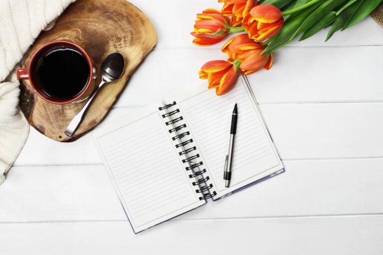 notebook on table with coffee and flowers.